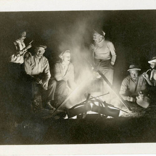 Black and white photograph of a group of men at a fire at night.